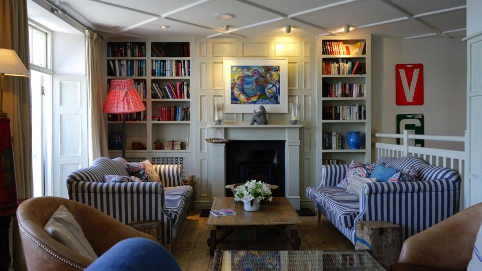 Cosy sitting room with bookshelves, striped armchairs and a fireplace